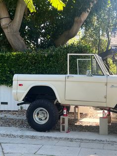 a white truck parked on the side of a road next to a tree and fence