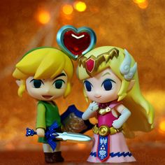 two figurines are standing next to each other with a heart on it's head