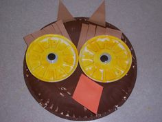 a paper plate with an owl made out of construction paper and oranges on it