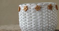 a white crocheted basket sitting on top of a wooden table