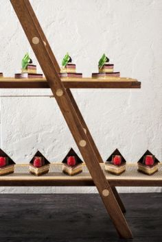 a long wooden shelf with small cakes on it's sides and two rows of smaller ones at the bottom