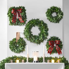 wreaths and candles are arranged on the mantle