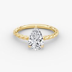 a yellow gold engagement ring with a pear shaped diamond in the center and twisted band