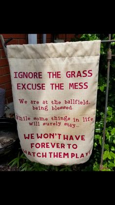 a large bag with words on it sitting in front of a fence and bushes behind it