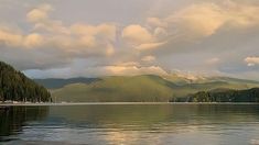 a lake with mountains in the background under cloudy skies