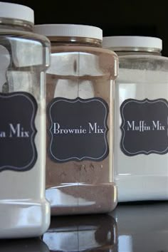 three glass jars with labels on them sitting on a counter next to another jar filled with brownie mix