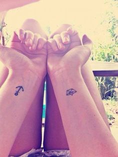 two girls with matching tattoos on their arms, both holding each other's hands