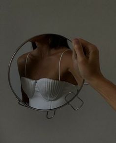 a woman's hand is holding up a mirror to show her bra on it