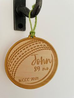 a wooden medal hanging from the side of a white wall next to a black hook