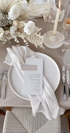 a place setting with silverware and white flowers