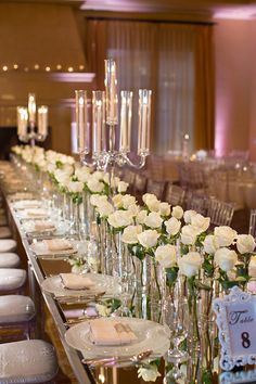 the long table is set with white roses and place settings for guests to sit at