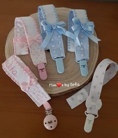 three baby girl pacifier clips and lanyards on top of a wooden table