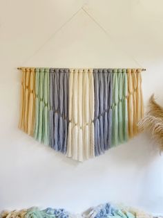 a multicolored wall hanging on a white wall next to a bed with pillows