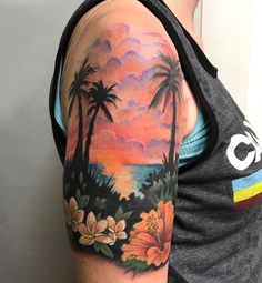 a man's arm with palm trees and flowers painted on the back of it