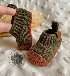 someone is holding their hand up to some crocheted shoes