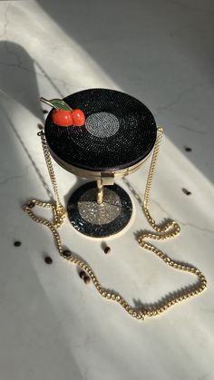 a black and white purse with a cherry on it's top sitting on a chain