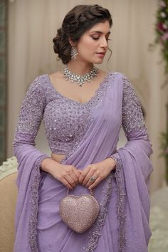 A photo of a Pakistani bride wearing a stunning purple saree. The saree has intricate embellishments and is paired with a blouse that features shimmering details and clusters of sequins and beads. Wedding Saari Designs Latest, Reception Saree Ideas, Engagement Lehenga Indian Simple, Saree For Reception Brides, Reception Dress Bride Indian Lehenga, Pakistani Saree Designs, Lehenga For Reception Bridal, Engagement Dress For Bride Indian Gown, Purple Saree Look