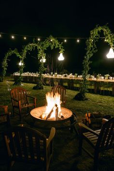 an outdoor fire pit with chairs around it and string lights hanging above the firepit