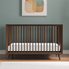 a baby's crib in front of a green wall with a painting on it