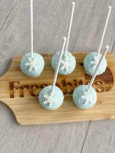 four cake pops on a wooden tray with white frosting