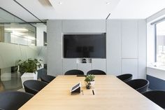 an empty conference room with a flat screen tv on the wall and black chairs in front of it