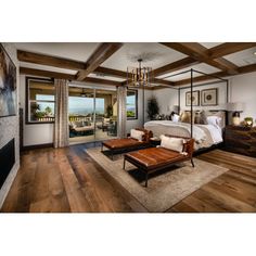 a bedroom with wood floors and white walls, large bed in the center surrounded by wooden beams