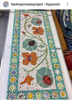 a mosaic tile floor with flowers and leaves on the bottom, surrounded by other tiles