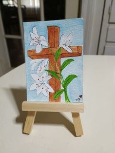 a cross with flowers painted on it is sitting on a easel in the kitchen