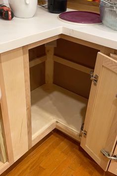 a kitchen with wooden cabinets and white counter tops in the corner, next to an empty dishwasher