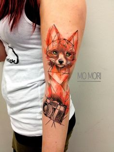 a woman's arm with a fox and camera tattoo on it