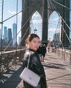 a woman is standing on the brooklyn bridge