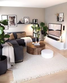 a living room filled with lots of furniture and plants on top of a white rug