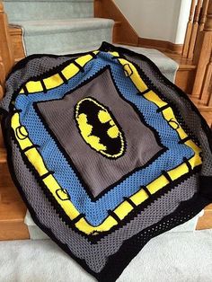 a batman backpack sitting on top of a wooden chair next to a window sill