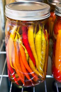 jars filled with pickled peppers sitting on top of a rack