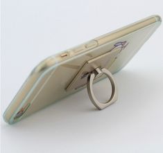 a cell phone with a ring attached to it's back end, sitting on top of a white surface