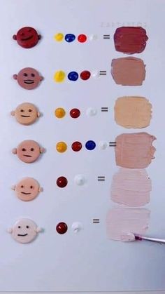 a person holding a paintbrush in front of an art board with different colored faces on it