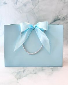 a blue gift bag with a light blue bow