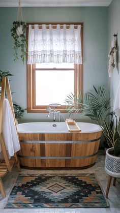 a bath tub sitting under a window next to a rug and potted palm tree