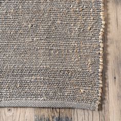 an area rug on top of a wooden floor with wood grains in the background