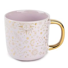 a white and gold coffee cup with stars, moon and sun designs on the side