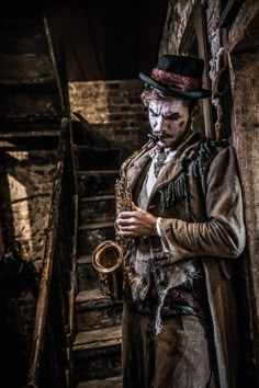 a man dressed as a clown playing the saxophone in an alleyway with stairs leading up to him