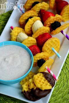 some waffles and strawberries are on a plate with a bowl of dip