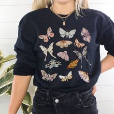 Introducing the Moth Sweatshirt, a captivating fusion of granola girl, fairy core and goblincore fashion. This biology-inspired shirt features a stunning Moth design, blending nature and fantasy seamlessly. With its cozy fit and witchy warmth, this enchanting garment is perfect for those who love to embrace the magical realms and express their unique style. Embody the allure of Moths and immerse yourself in the mystical world of goblincore with the Moth Sweater. **Size UP for Oversized Look** Th Fairycore Long Sleeve Tops For Spring, Spring Fairycore Long Sleeve Tops, Long Sleeve Fairycore Tops For Spring, Fairy Grunge Long Sleeve Graphic Top, Fairy Grunge Long Sleeve Top For Fall, Fall Fairy Grunge Cotton Tops, Fairy Grunge Cotton Tops For Fall, Black Long Sleeve Goblincore Top, Black Fairy Grunge Tops For Fall