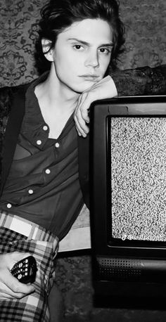 black and white photograph of a woman sitting in front of a tv with her hand on her chin