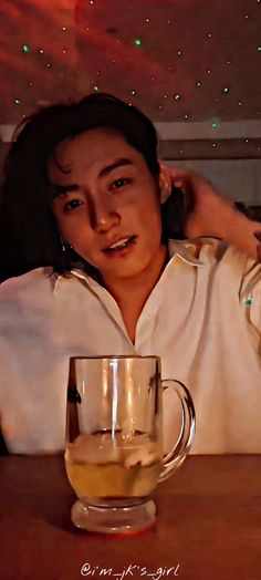 a woman sitting at a table next to a glass cup with liquid in it and stars on the ceiling behind her