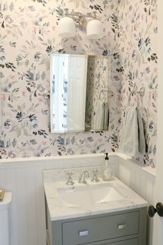 a white sink sitting under a bathroom mirror next to a wall mounted faucet