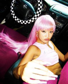 a woman with pink hair sitting in a car