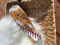 a wooden baseball bat sitting on top of a white fur covered floor next to a basket