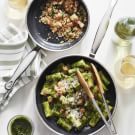 two bowls filled with broccoli and other food on top of a white table