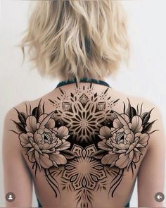 the back of a woman's body with tattoos on her chest and flowers painted on it